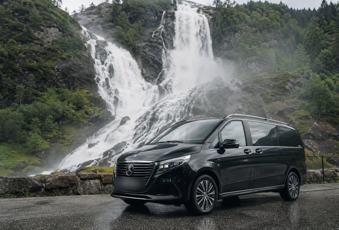 A black Mercedes people carrier by a waterfall